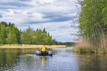 Fisherman in an inflatable boat floats and fishing on the lake.