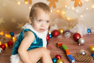 Fototapeta na wymiar a little boy in a blue Christmas suit. a boy plays with a toy train