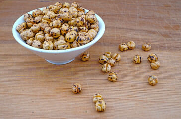 Plateful of Organic Roasted spicy chickpeas and Spilled chickpeas on Wooden Background