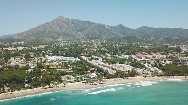 Cinematic aerial view of exclusive area in Marbella, Casablanca beach, golden mile. La Concha mountain in background. Most expensive area from south of Spain, Costa del sol. Drone going backward.