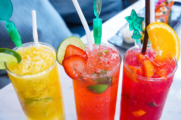3 drinks of cocktails on the table, strawberry lime and orange slices