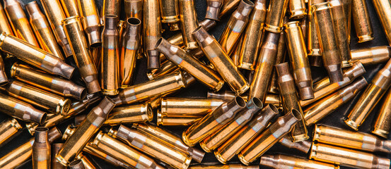 Empty cartridge cases for a carbine or rifle. Background of shiny brass cartridges for cartridges to illustrate armed conflict, war or shooting events. © solidmaks