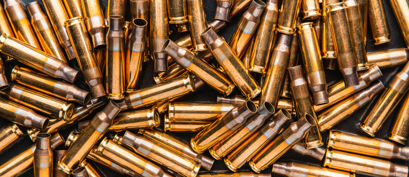 Empty cartridge cases for a carbine or rifle. Background of shiny brass cartridges for cartridges to illustrate armed conflict, war or shooting events.