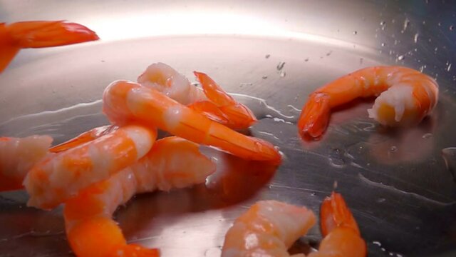 Close-up of large shrimps falling in a water with splashes on the pan. Shrimp Recipe