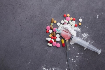 Heroine, syringe and pills on wooden background.