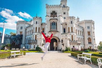young woman in a red jacket near the castle is deep over vltava