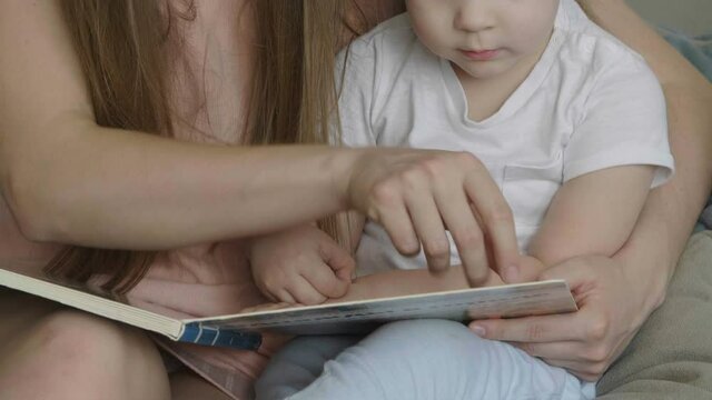 Caring single parent young mother babysitter hug happy cute little preschool child girl kid daughter hold learn read book fairy tale story bonding enjoying family lifestyle hobby at home sit on couch