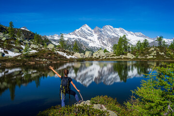 Woman with arms outstretched on mountain. One person looking at view scenic lake alpine landscape summer vacation fitness wellbeing freedom concept