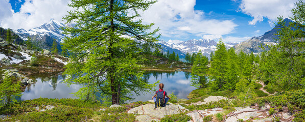 Woman meditating in natural environment on the mountains. One person sitting on rock in lotus pose in beautiful alpine ambient.