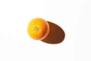 Fresh juicy orange on a white background with a hard shadow. Top view