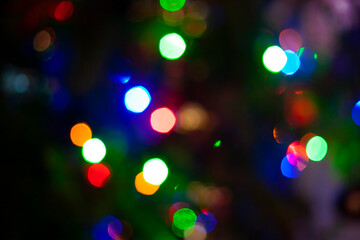 Multi color bokeh background from Christmas, New Year, festive or party light on dark