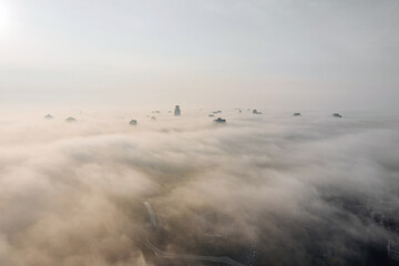 Fototapeta premium Aerial view of the city in the fog. Skyscrapers above the fog