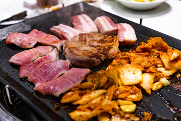 Korean BBQ Raw Pork on the Grill with Kimchi.