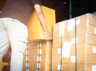 Warehouse worker lifting shipment boxes, cartons, cardboard box, warehouse delivery service shipping goods at manufacturing warehouse.