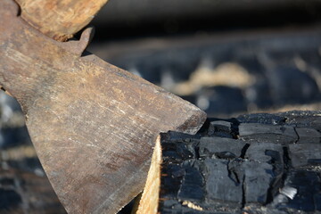 Close up of the blade of an old axe with a wooden handle stuck in a stump in the yard of a country house