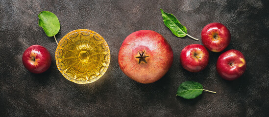 Jewish New Year - Rosh Hashanah, banner. Apples, pomegranate and honey on a dark rustic background, border. Traditional Jewish food. Top view, flat lay.