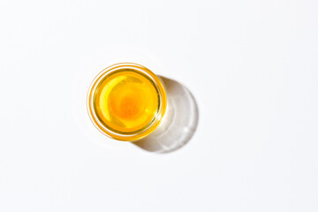 Honey in a small glass plate on a white background. Nearby lies a wooden spoon