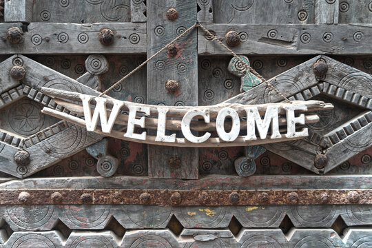 Wood white welcome sign hanging  on antique rustic wooden door