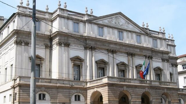 Scala building from the street - Scala theater for ballets and classical music concerts Opera - One of the symbols of Milan - Teatro della Scala of Milan with European and italian flag - Real Time