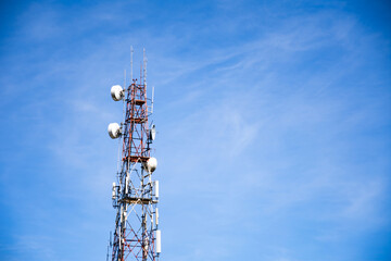 Telecommunication tower wireless technology against blue sky and clouds.