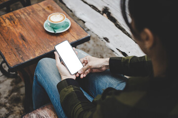 Fototapeta premium cell phone mockup image blank white screen.woman hand holding texting using mobile on desk at coffee shop.background empty space for advertise.work people contact marketing business,technology