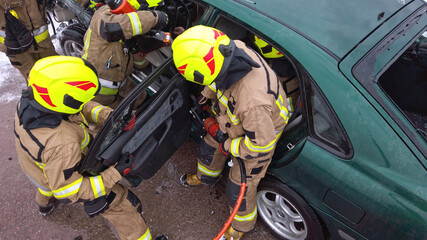 Team off Firefighters trying to cut open car door to save person involved in the accident. 