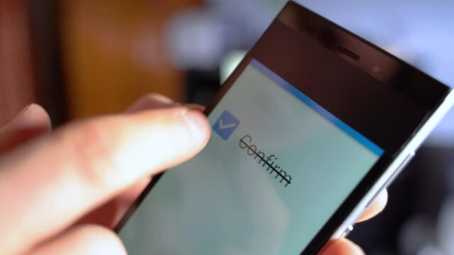 Confirm majority check symbol on the phone. Man Hand holding smartphone with vote button on the screen CONFIRM