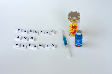 Vaccine and capsules vitamin C on a white background with wording "VACCINE AND VITAMIN".