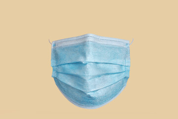 Medical surgical mask, front view, on ocher background.