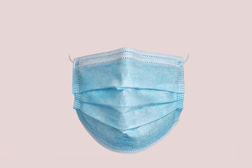 Medical surgical mask, front view, on pink background.