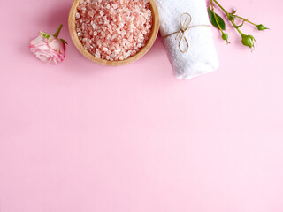Fototapeta na wymiar Spa flatlay composition. Sea salt in wooden jar, towel, flower on pink background. Top view, copyspace. Daily care concept, relax and rest, bath procedure