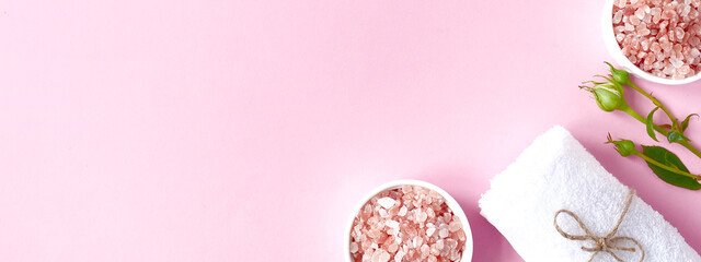 Spa flatlay composition. Sea salt in jar, towel, flower on pink background. Top view, copyspace, banner. Daily care concept, relax and rest, bath procedure