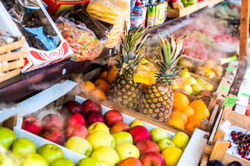 various fruits are sold on the market. red and green apples, oranges and pineapples, cherries. various sweets, candied fruits. cooled by air supply. bazaar. summer