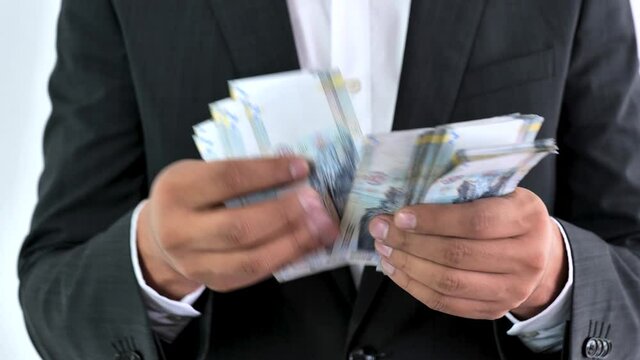Business man in a suit counting 100 soles bills. Peruvian currency concept, counting bank notes from Peru. Executive hispanic male holding one hundred notes.