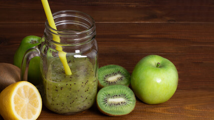 Blended green smoothie with kiwi and green apple on wooden background