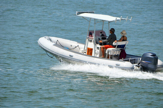 Middle Aged Couple Leisurely Cruising On Biscayne Bay Near Miami Beach,Florida In A. Pontoon Fishing Boat With Canopied Center Console Powered By Single Outboard Motor.