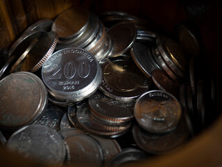 200 Rupiah coin among Thai baht coins. coin shine bright in piggy bank.