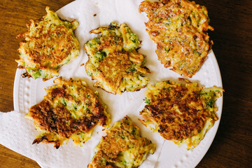 A great toddler meal idea, these vegetable fritters are made with shredded potato, frozen vegetables, egg, and cheese.  They are served on a white plate on a wood table. 