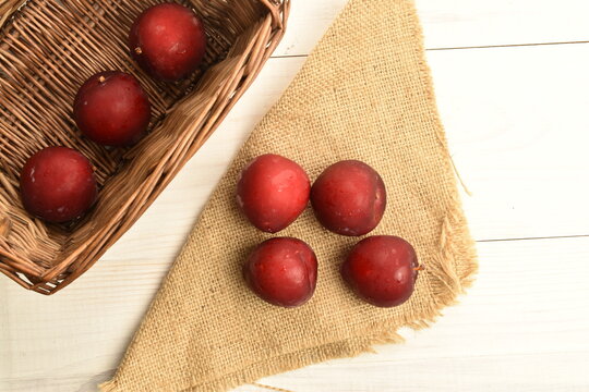 Fresh ripe, organic red plum, close-up, on a painted wooden table.