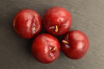 Fototapeta na wymiar Fresh ripe, organic red plum, close-up, on a serving plate of slate.