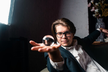 Young man holding a clear transparent crystal glass ball in their hand
