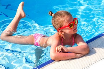 Little ballerina in the pool in summer. Happy little girl swimming in the pool on vacation. Happy childhood