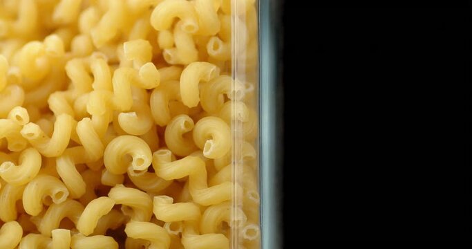 Cavatappi pasta dry falls in a glass jar.