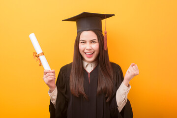 Portrait of happy Beautiful woman in graduation gown is holding education certificate on yellow background