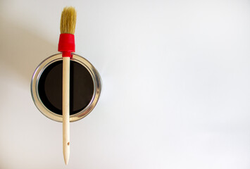 A round paint brush lies on a can of paint on a white background. Copy space.