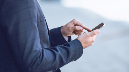 Cropped view of young entrepreneur checking email on mobile phone outside