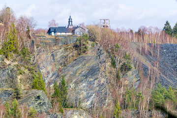 Gebäude aus Schiefer mit Kirchturm an der Spitze eines Schieferberges. Historisches Schiefer Abbau...