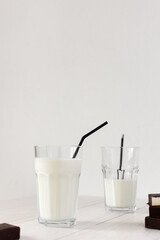 Fresh milk in a glass with black straws, chocolate candies with souffle, tasty healthy drink