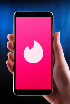 Hands holding smartphone displaying logo of Tinder