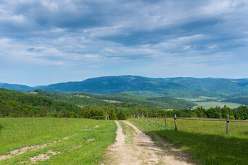Dirt road near wood fence leading trough the countryside in the Carpathian mountains in Romania.